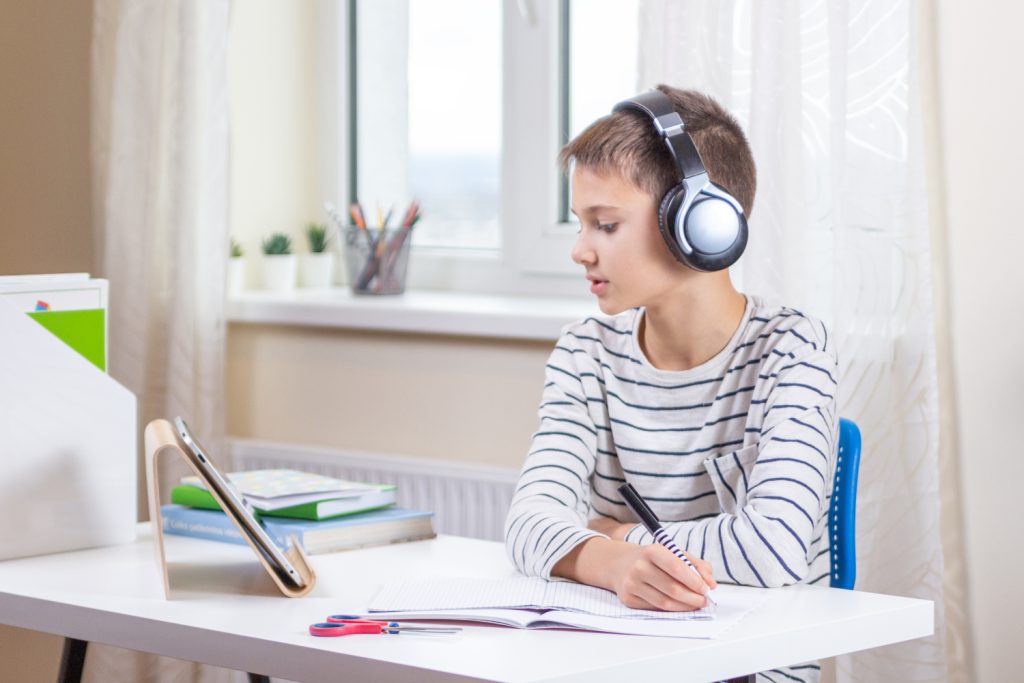 Online learning, remote education, distance lessons at home. Kid with digital tablet computer sitting at desk with books and having video call, virtual online leasson, making homework at home
