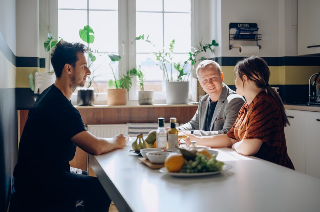 Photo of VM.PL employees talking around a shared table in the office kitchen. Team members are enjoying a break and having an informal conversation in a relaxed atmosphere.
